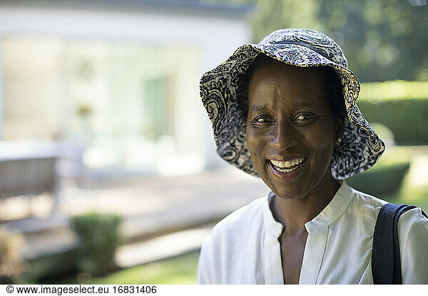 Portrait happy mature woman in sun hat in summer backyard
