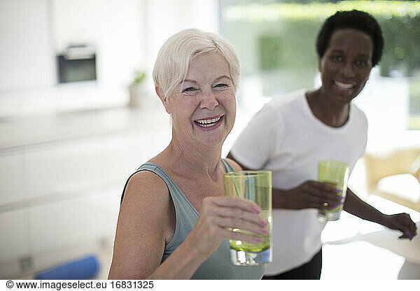 Portrait happy senior women friends drinking water at home