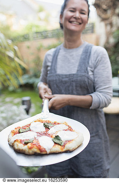 Portrait happy woman cooking fresh homemade pizza outdoors