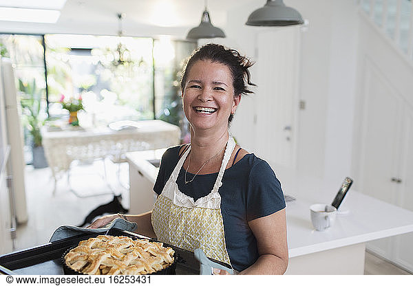 Portrait happy woman with fresh homemade apple pie in kitchen