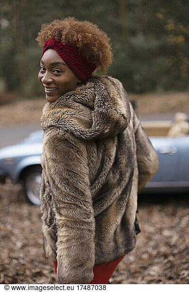 Portrait happy young woman in fur coat in autumn park