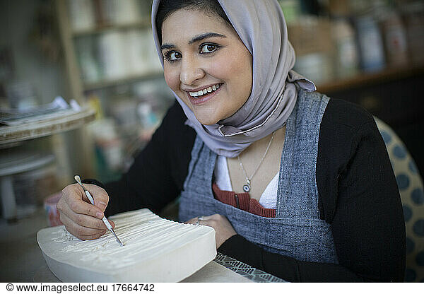 Portrait happy young woman in hijab in art studio