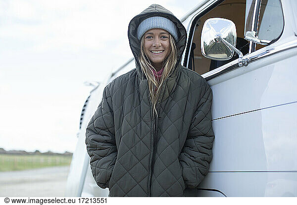 Portrait happy young woman in hooded coat outside van