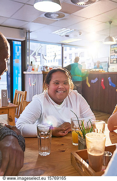 Portrait happy young woman with Down Syndrome in cafe with friends