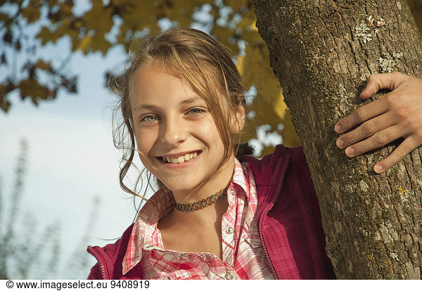 Portrait lächeln Baum halten Baumstamm Stamm Mädchen