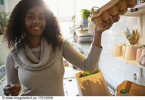Portrait lächelnde Frau beim Auspacken von Lebensmitteln in der Küche