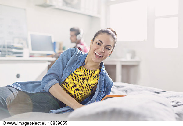 Portrait lächelnde junge erwachsene Frau beim Lesen im Bett