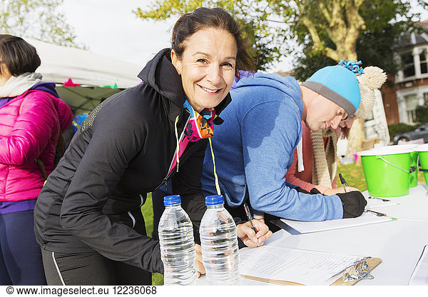Portrait lächelnde Läuferin beim Einchecken beim Charity Run im Park