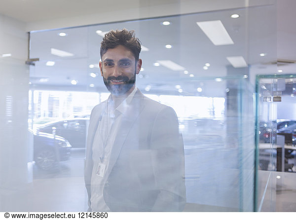 Portrait lächelnder  selbstbewusster Autoverkäufer im Autohaus-Showroom