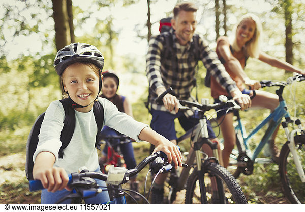 Portrait lächelndes Mädchen Mountainbiken mit Familie im Wald