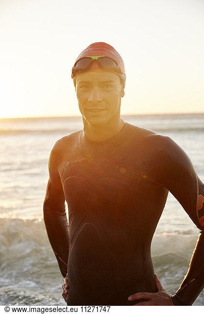 Portrait male triathlete swimmer in wet suit in ocean surf