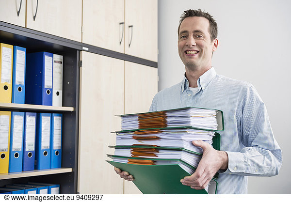 Portrait man carrying pile filing folders