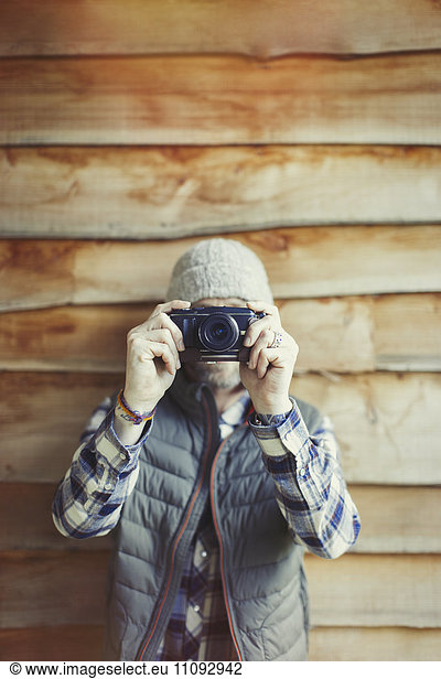 Portrait man using camera outside cabin