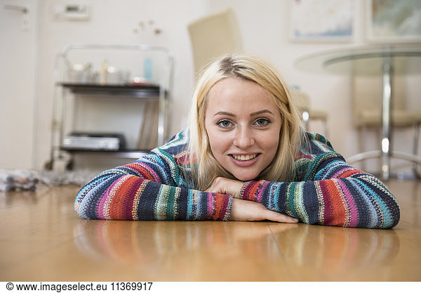 Portrait of a beautiful young woman lying on floor in the living room