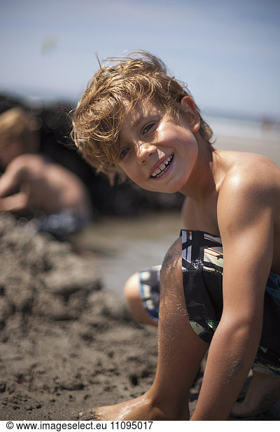 Portrait of a boy building a sandcastle and smiling on the beach  Viana do Castelo  Norte Region  Portugal