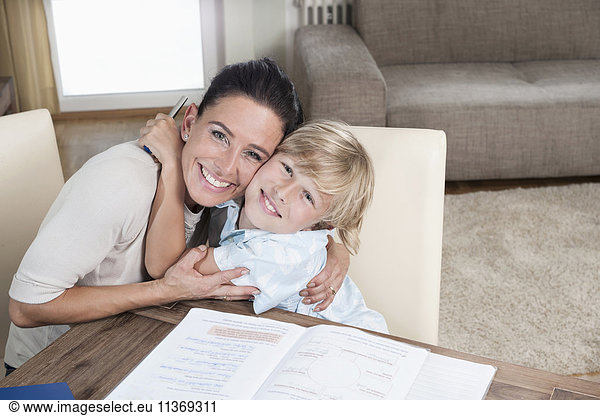 Portrait of a boy embracing his mother while studying
