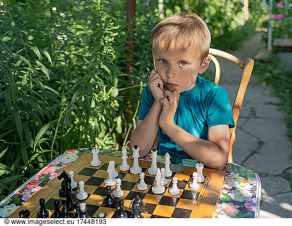 portrait of a boy playing chess in the garden