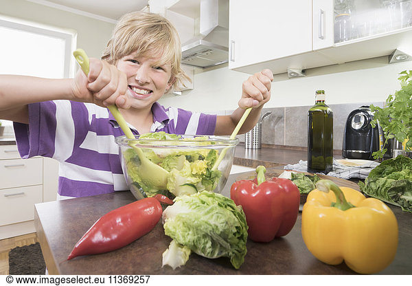 Portrait of a boy preparing salad in kitchen