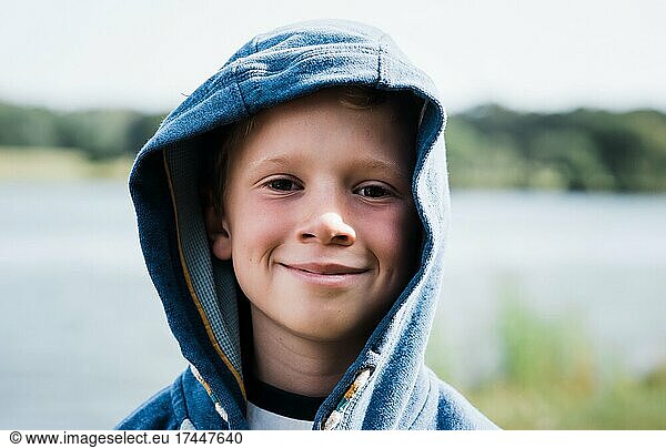 portrait of a boy smiling with his hood up at the beach