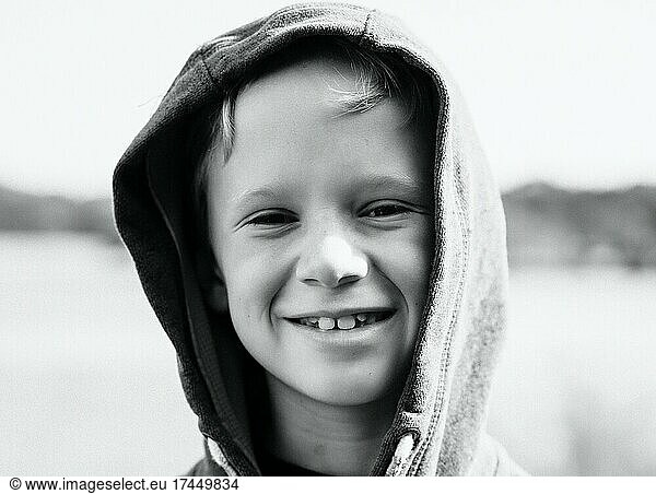 portrait of a boy smiling with his hood up at the beach