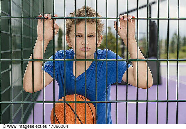 Portrait of a boy with a basketball on the playground.