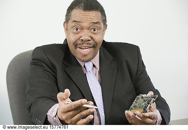 Portrait of a businessman holding a computer chip and a pen