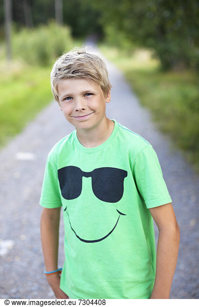 Portrait of a Caucasian pre-adolescent boy standing on road smiling