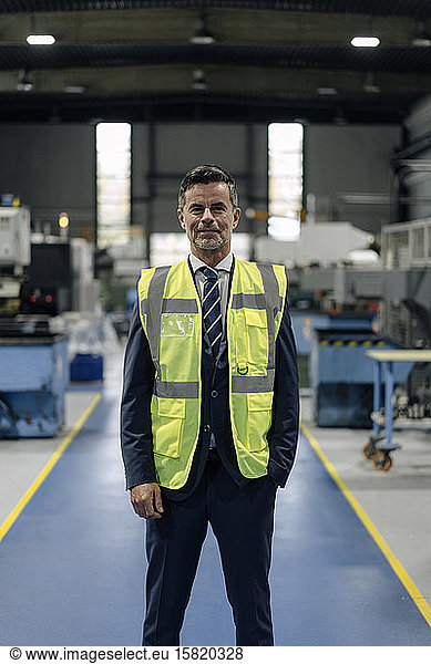 Portrait of a confident businessman wearing a reflective vest in a factory