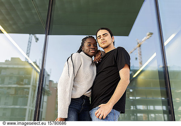 Portrait of a confident young couple standing at a glass front