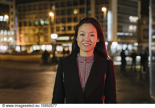 Portrait of a confident young woman in the city at night  Frankfurt  Germany