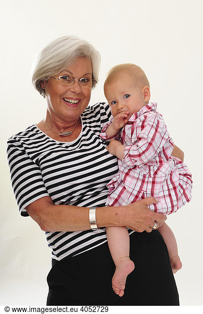 Portrait of a congenial woman  60 years old  senior citizen  with grey hair  holding her grand-daughter in her arms