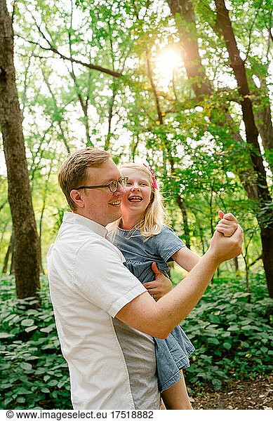 Portrait of a father and daughter dancing together in the forest
