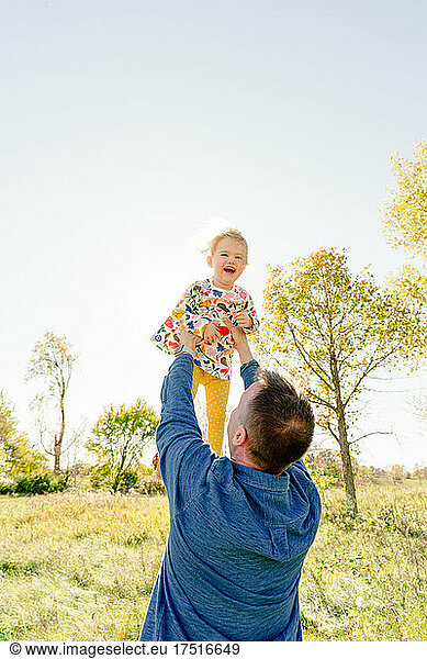 Portrait of a father throwing his toddler daughter into the air