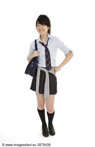 Portrait of a female Asian teenager dressed in the traditional Japanese schoolgirl clothing Uniforms are worn by most of the female school children in Japan She is standing on a white background and smiling