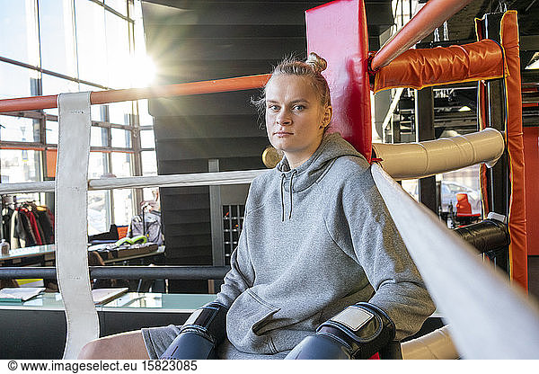 Portrait of a female boxer in gym sitting in ring corner