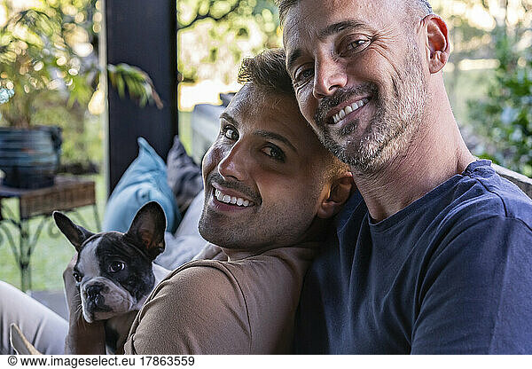 Portrait of a gay male couple and their french bulldog.