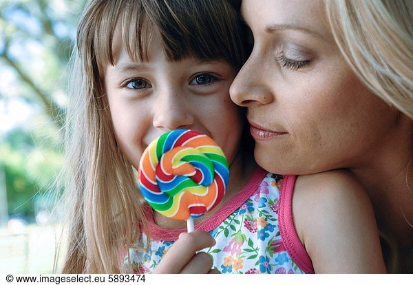 Portrait of a girl holding a lollipop with her mother