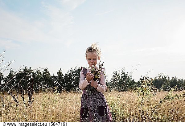 portrait of a girl holding wild flowers in a meadow at sunset