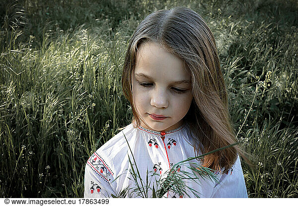 Portrait of a girl in an embroidered shirt with spikelets outdoors
