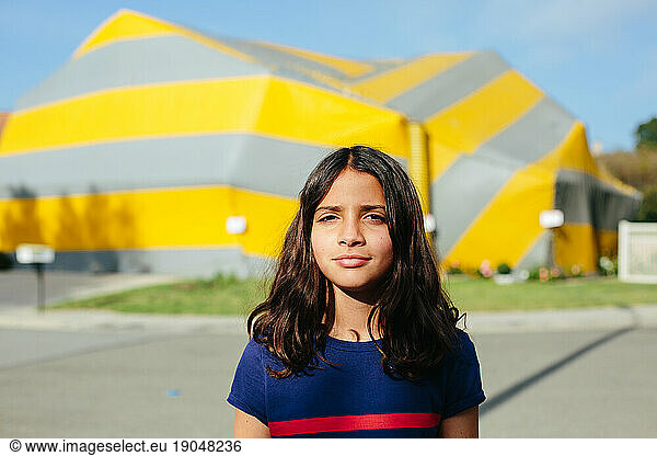 Portrait of a girl outside with a tented house in the background