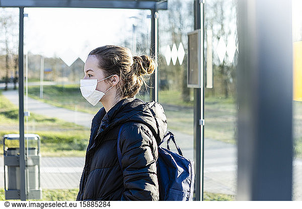 Portrait of a girl with mask waiting at bus stop