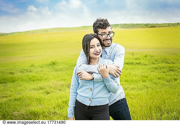 Portrait of a happy couple hugging in the field  Portrait of a young couple in love in the green field looking at the camera  Portrait of a cute couple in the field looking at the camera