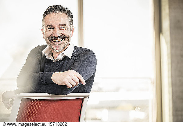 Portrait of a happy mature businessman sitting on chair in office