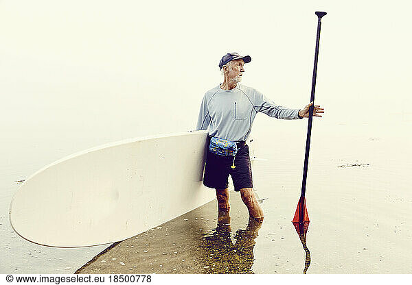 Portrait of a mature man and his paddle board after a paddling trip