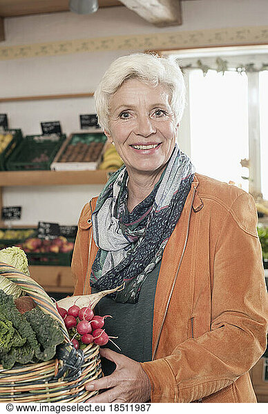 Portrait of a mature woman buying vegetables in the farm and smiling  Bavaria  Germany