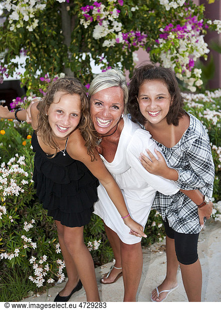 Portrait of a mother with two thirteen-year-olds girls in front of flowers