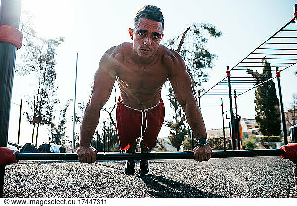 Portrait of a muscular Man doing a push-up on a barbell.