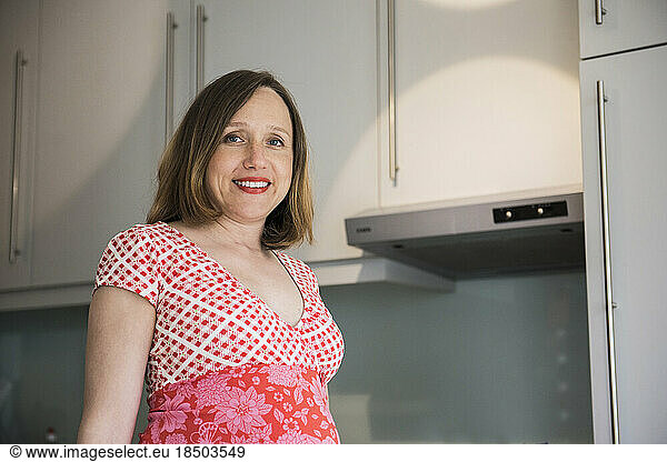 Portrait of a pregnant woman standing in the kitchen and smiling  Munich  Bavaria  Germany