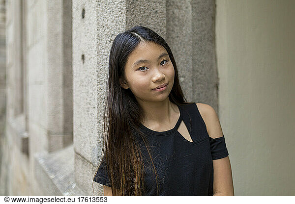 Portrait of a preteen girl leaning against a stone wall; Hong Kong  China