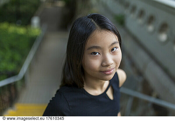 Portrait of a preteen girl standing on steps in a park; Hong Kong  China